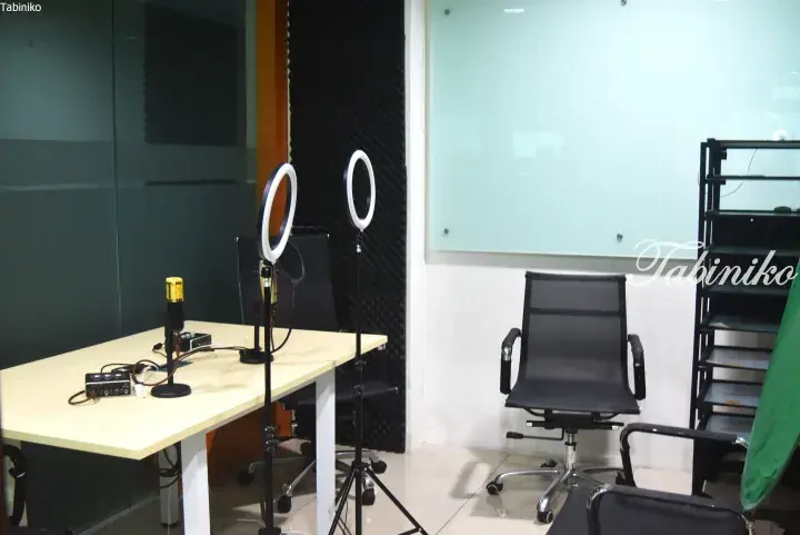 Home studio setup with ring lights, microphone, and office chairs in a modern room.