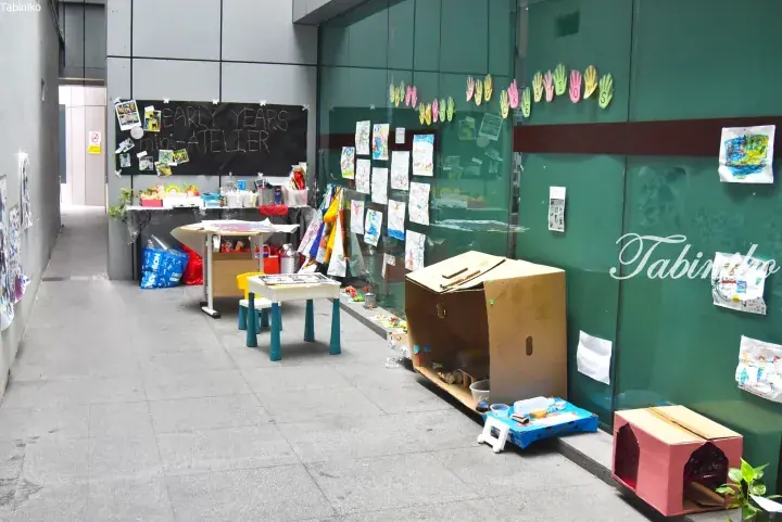 Children’s art display area with handprints and drawings on glass walls, featuring a chalkboard sign reading ‘Early Years Mini-Atelier’.