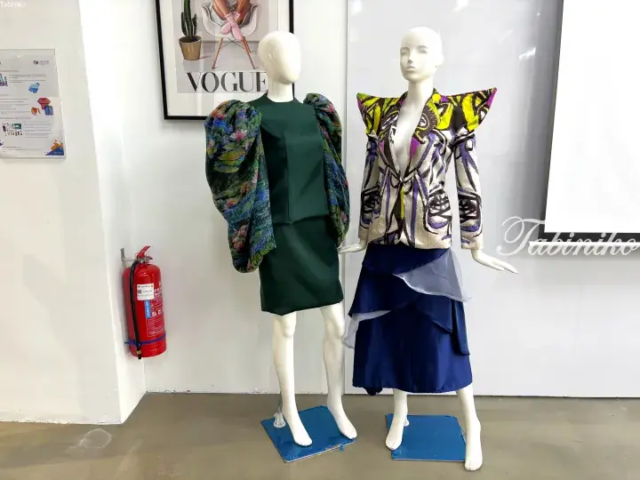 Two fashion mannequins display avant-garde outfits with bold patterns and dramatic silhouettes in a studio setting.