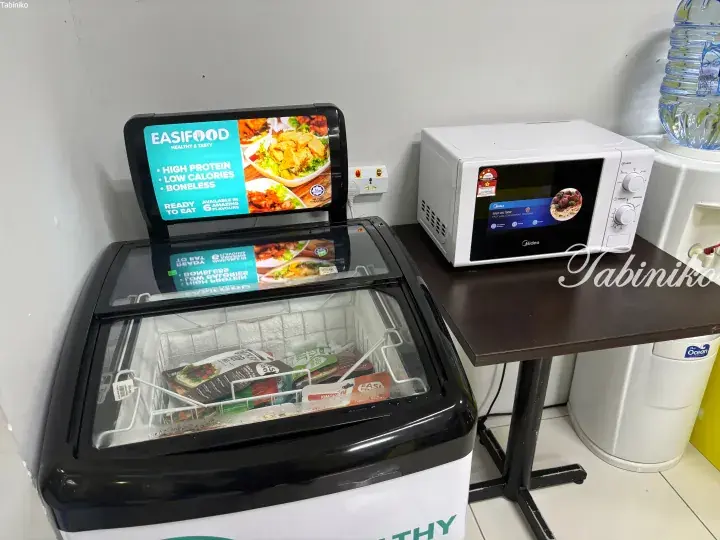 Easifood healthy frozen meals display in a chest freezer next to a Midea microwave on a table.