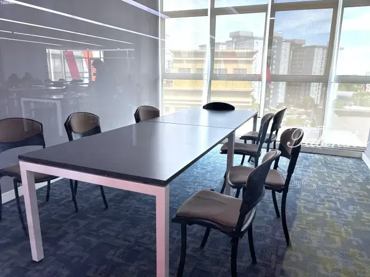 Modern meeting room with a long conference table, chairs, and large windows overlooking a cityscape in Malaysia.
