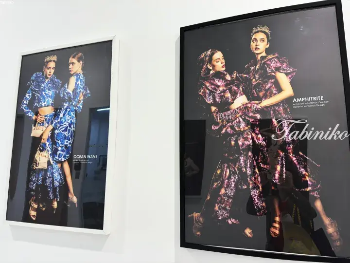 Framed fashion design student portfolios titled Ocean Wave and Amphitrite displayed on a white gallery wall.