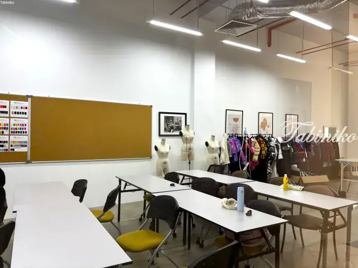 Bright fashion design studio with mannequins, fabric swatches, and work tables.