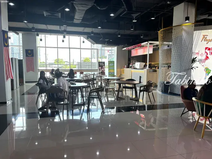 San Francisco Coffee shop interior with tables, chairs, and Malaysian flags near large windows.
