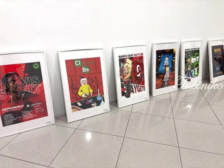 Framed pop culture posters including Travis Scott, Clucking Bad, and Baygette displayed on a tiled floor.