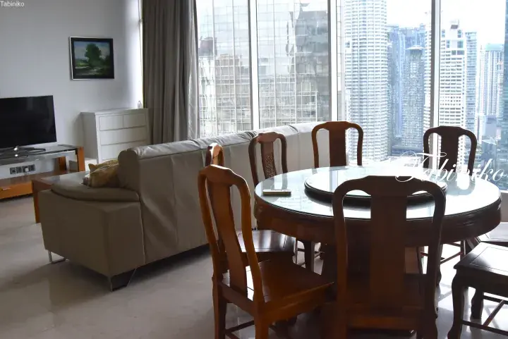 Modern living room with a round dining table and city skyline view from a high-rise apartment in Kuala Lumpur.