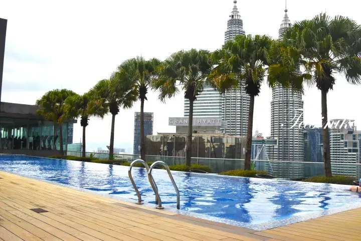 Rooftop infinity pool with palm trees overlooking the Petronas Twin Towers and Grand Hyatt Kuala Lumpur.