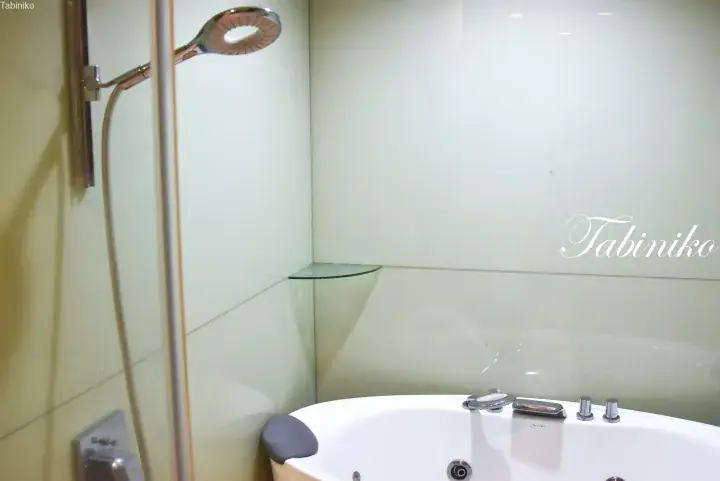 Modern bathroom featuring a white bathtub with chrome fixtures and a glass shower screen.