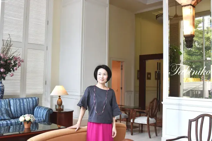 Woman standing in the elegant lobby of a luxury hotel in Malaysia, featuring classic furniture and large windows.