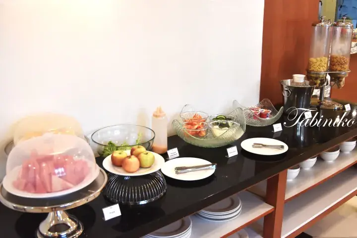 Buffet spread featuring fresh fruits, mixed salad, yogurt, and cereal dispensers at a hotel dining area.