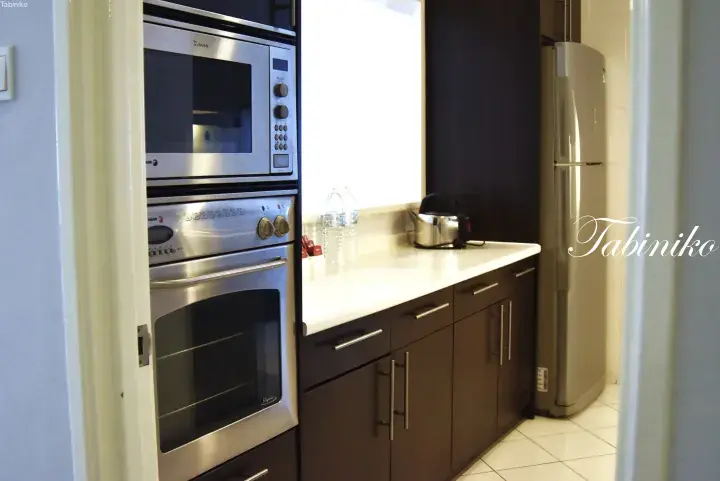 Modern kitchen with stainless steel built-in oven, microwave, kettle, and refrigerator in a property.