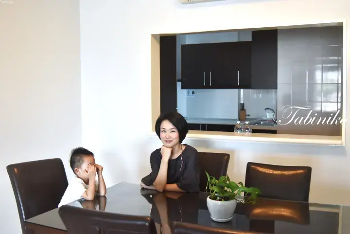 Woman and young boy sitting at a dining table in a modern apartment with a view of the kitchen.