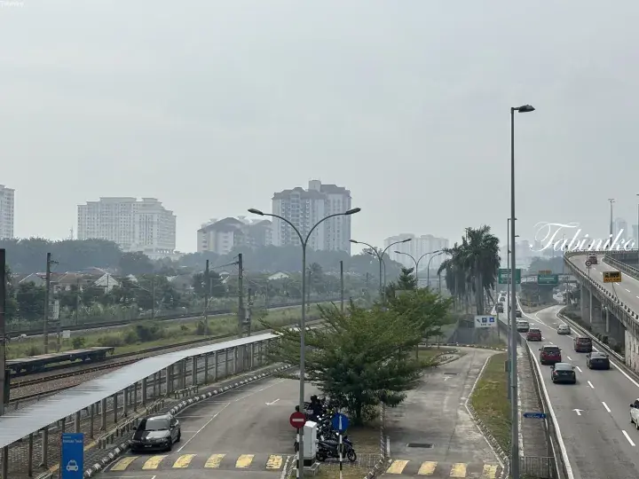 View of Serdang LRT station taxi stand and highway with apartment buildings in the background.