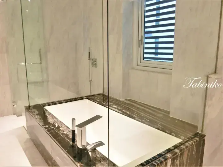 Modern bathroom featuring a deep soaking tub with dark marble surround and a glass-enclosed shower area.