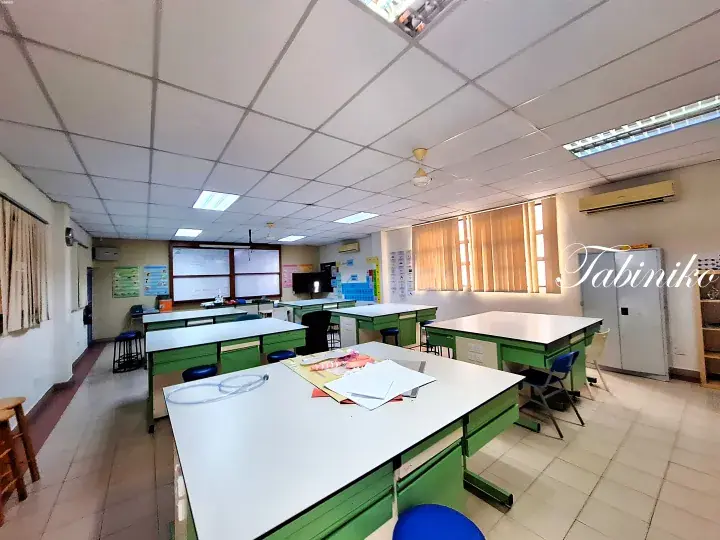 Spacious classroom with green lab tables, whiteboards, and ceiling fans in a Malaysian school.