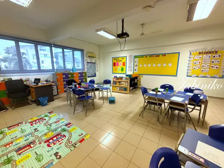 Bright classroom with blue desks, colorful bulletin boards, and a road-themed rug.