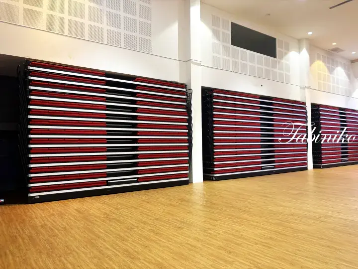 Stacked red and white folding chairs in a modern hall with wooden flooring.