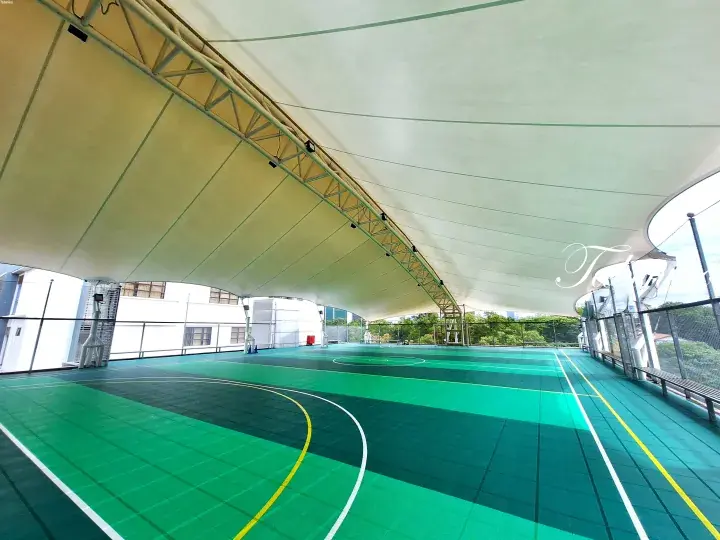 Spacious covered sports court with green flooring and white tensile roof structure, featuring multiple court markings.