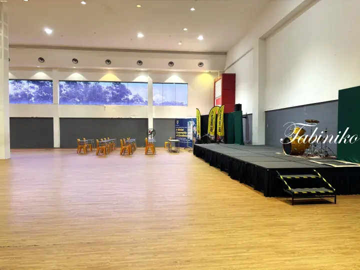 Sri Inai International School hall with stage, drum set, and orange chairs ready for event.