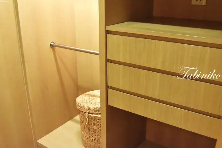 Light wood wardrobe with drawers and hanging rail, featuring a woven laundry basket in a modern Malaysian home.