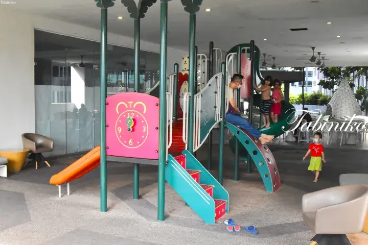 Children playing on a colorful playground structure with a slide and clock panel at a residential facility.