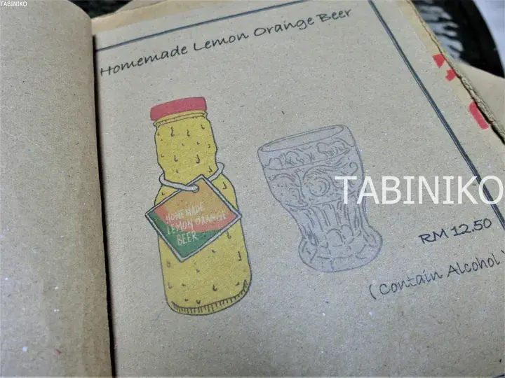 自家製レモンオレンジビールのボトルとグラスが描かれた手書きのメニューページ