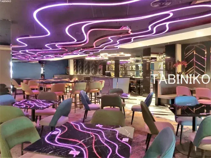 Modern restaurant interior with purple neon ceiling lights and colorful chairs