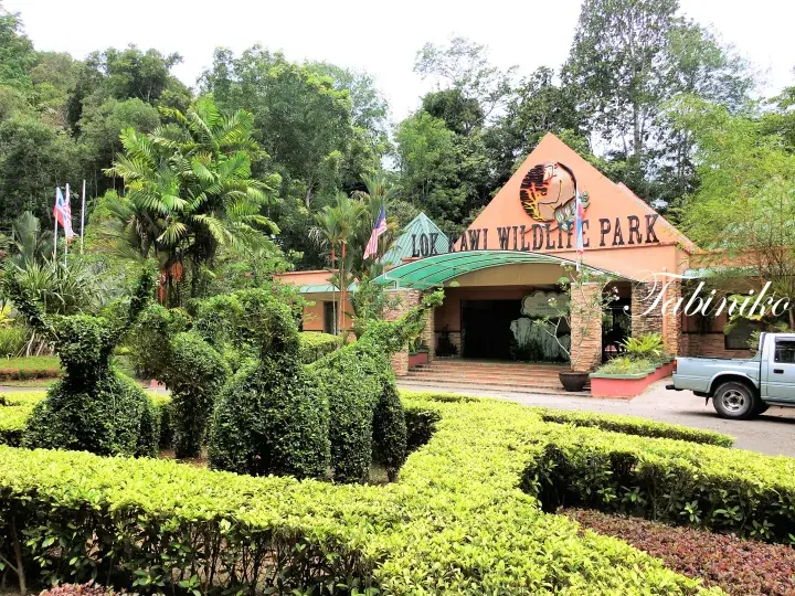 熱帯植物に囲まれたLok Kawi Wildlife Parkのオレンジ色の入口ビル。