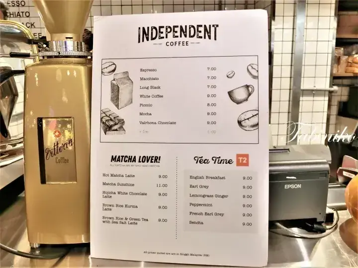 クリーム色のOttaviaコーヒーグラインダーの隣に置かれた、Independent Coffeeのメニューボード。