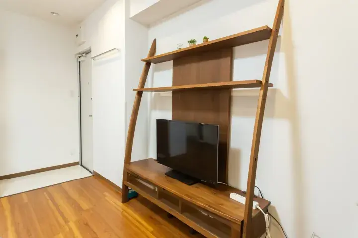 Modern wooden ladder shelf unit with TV stand in a bright room with hardwood floors and white walls