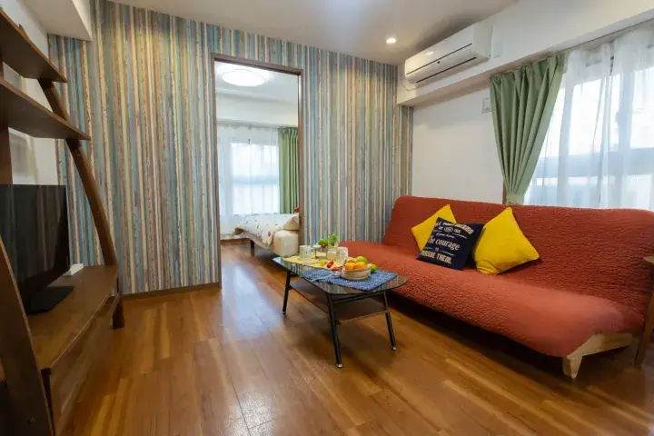 Cozy living room with orange sofa, striped wallpaper, and wooden floors in a Malaysia apartment.