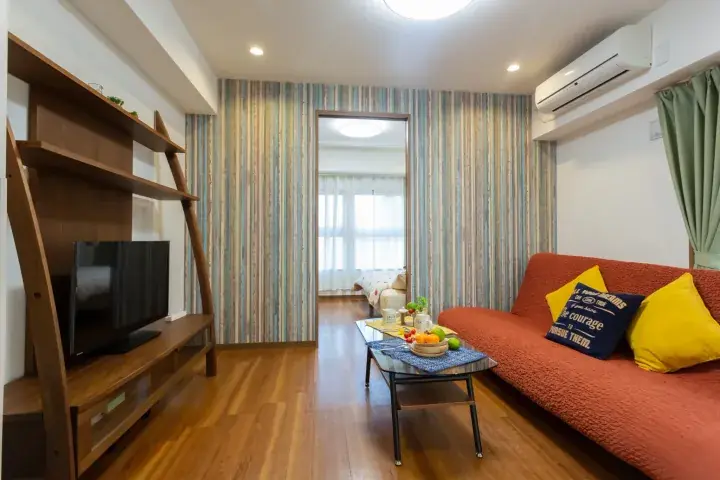 Cozy living room with orange sofa, wooden TV stand, and striped wallpaper in a modern apartment.