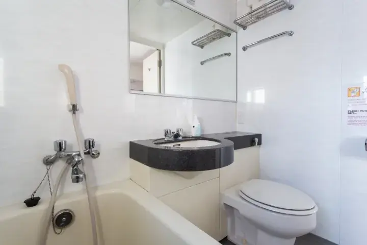 Modern bathroom with a bathtub, sink, and mirror in a clean white interior.