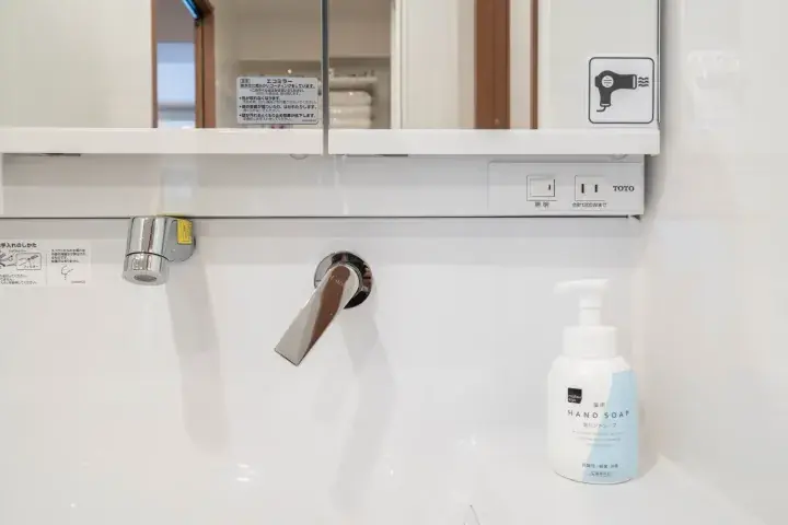 Modern bathroom sink with TOTO faucet and hand soap dispenser in a clean white interior