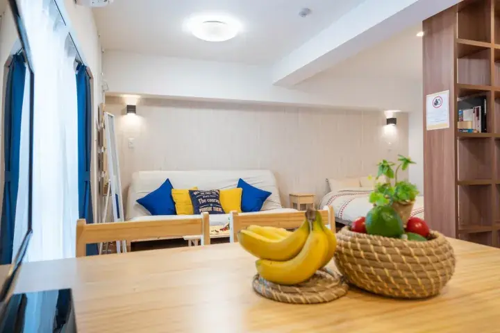 Bright living area with sofa, wooden dining table, and fruit basket in a modern Malaysian apartment.