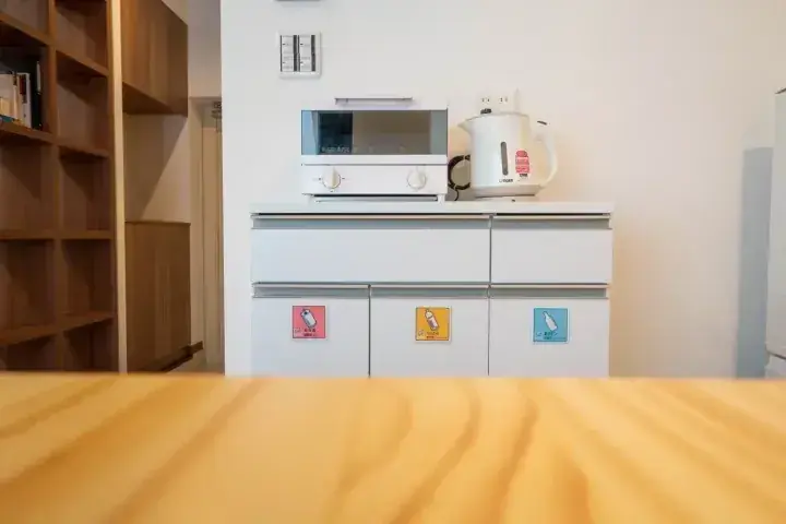 電子レンジやかぼちゃ型電気ポットが置かれた、モダンな白いキャビネットのキッチン。