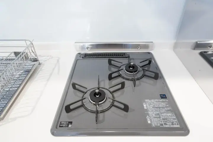 Modern two-burner gas stove installed in a sleek kitchen countertop with a dish rack nearby