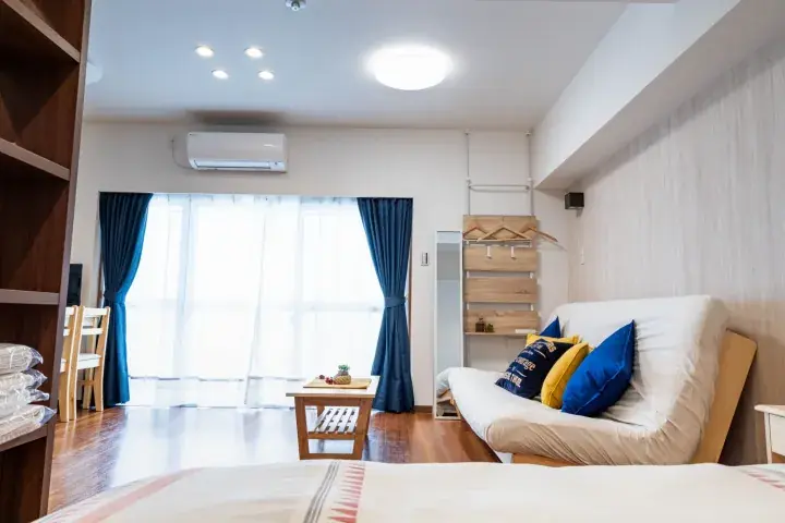 Bright living area with a white sofa, blue curtains, and wooden flooring in a modern Malaysian property.