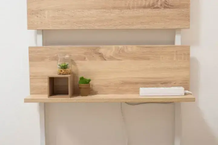 白い壁に取り付けられた木製のデスク、棚、観葉植物、電源タップ