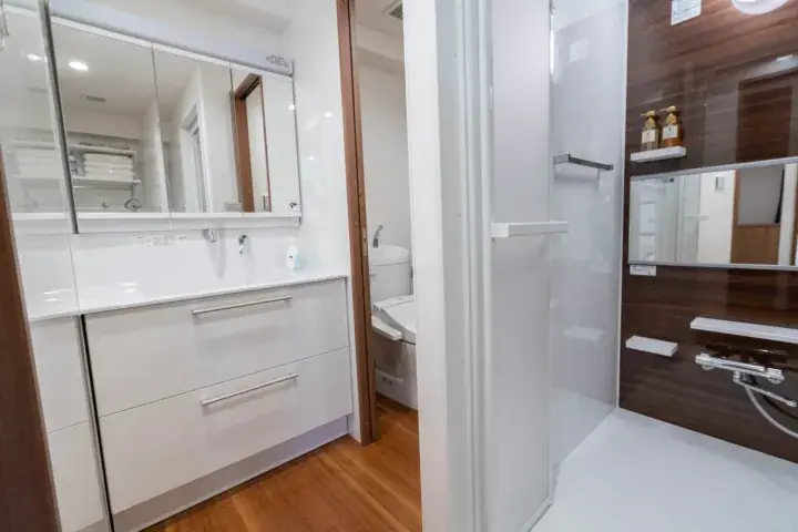 Modern bathroom with white vanity, mirror cabinet, and glass shower enclosure in a residential unit