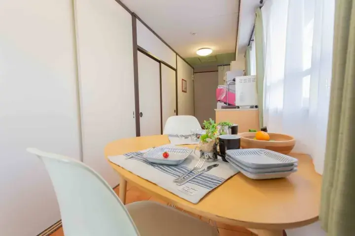 Bright dining area with wooden table, white chairs, and kitchen in a modern Malaysian apartment
