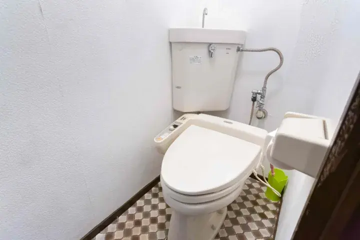 Compact Japanese toilet with bidet seat and tiled floor in a small bathroom
