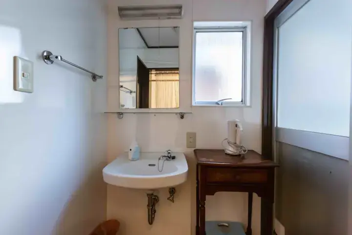 Compact bathroom with a white sink, mirror, and wooden table in a Malaysian property.