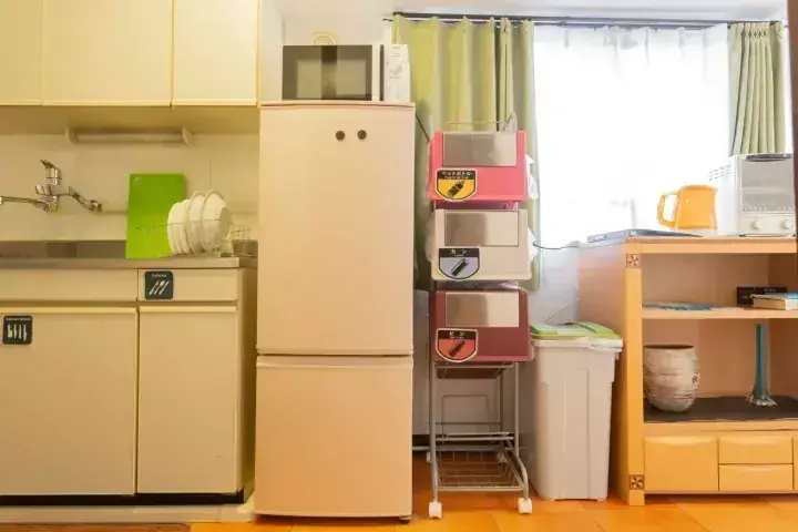 冷蔵庫や電子レンジ、食器棚が整然と配置されたコンパクトなキッチンのインテリア。
