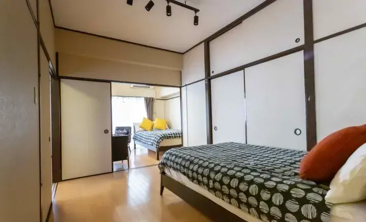 Modern Japanese-style bedroom with sliding doors, wooden floors, and a bed with patterned bedding.