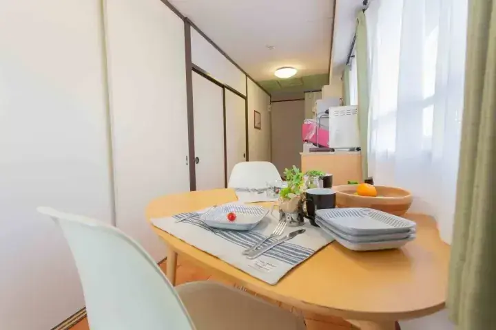 木製テーブルと白い椅子が並ぶ明るいダイニングとキッチン