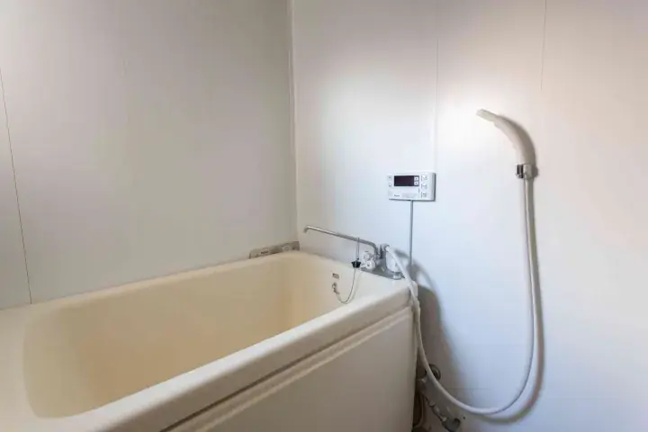 Clean white bathtub with shower hose and control panel in a modern bathroom