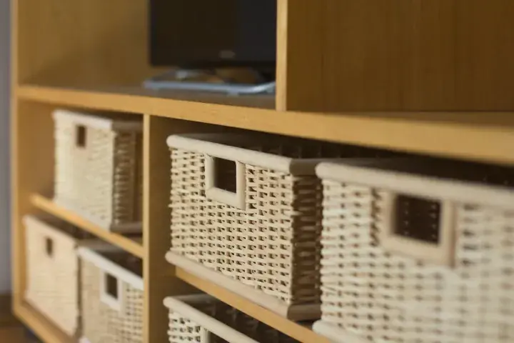 Close-up of woven storage baskets neatly arranged on light wooden shelves in a modern home interior.