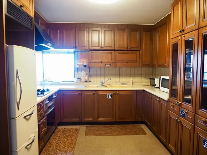 Spacious kitchen with wooden cabinets, white refrigerator, and large window in a Malaysian property.