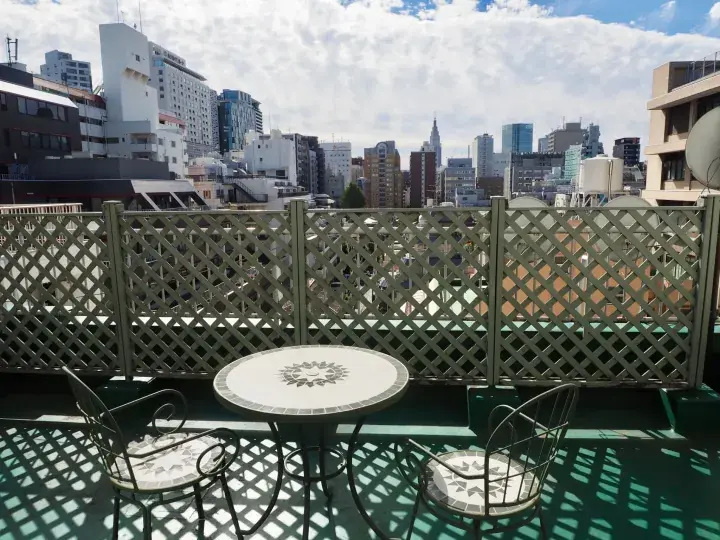 Rooftop terrace with a table and chairs overlooking a city skyline with a lattice fence.